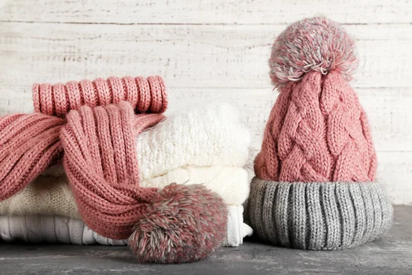 Knitted sweaters with scarf and hat on grey table — Stock Photo, Image