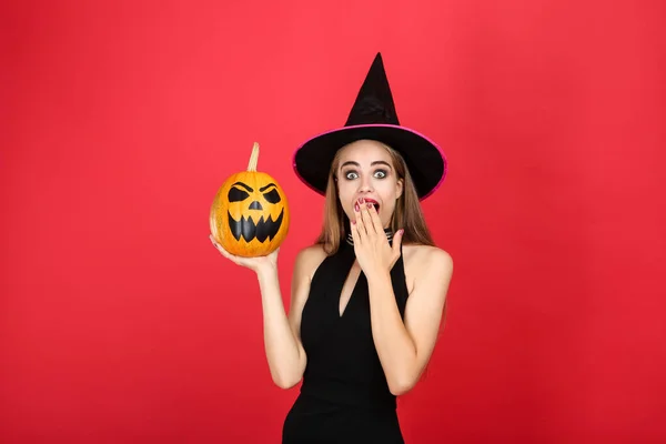Vacker kvinna i svart kostym håller Halloween pumpa på Re — Stockfoto
