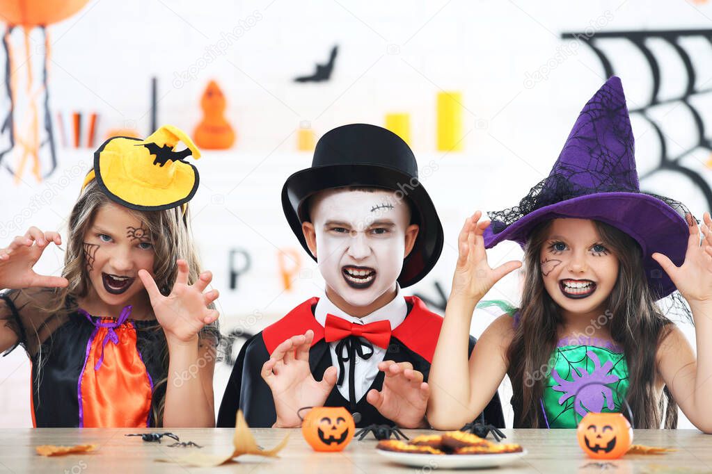 Beautiful two girls and boy in halloween costumes sitting by the