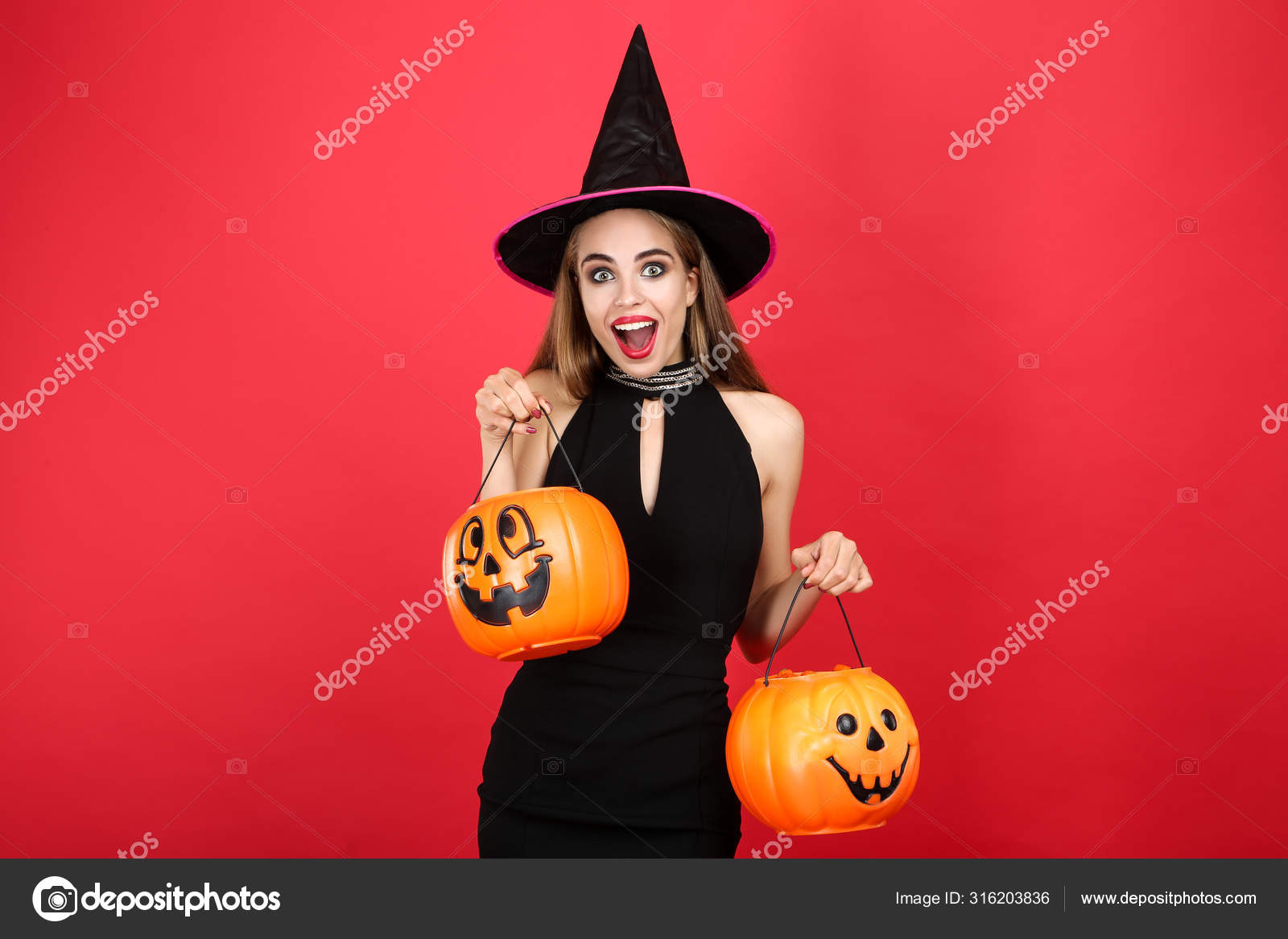 Beautiful woman in black costume holding halloween pumpkin bucke Stock