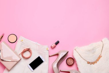 Pembe arka planda kozmetik ile şık kadın giysileri