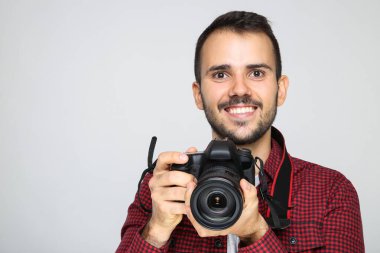 Gri arka planda kameralı genç fotoğrafçı