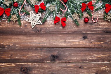 Noel ağacı dalları ve kahverengi ahşap üzerinde oyuncaklar ve şekerler.