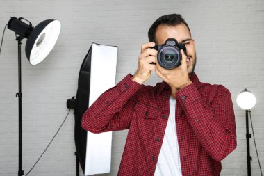 Kameralı ve profesyonel stüdyo ekipmanlı genç fotoğrafçı