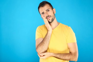 Portrait of young man having a toothache on blue background
