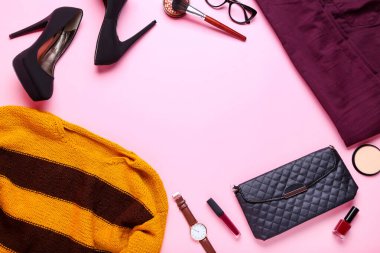 Pembe arka planda makyaj malzemesi olan modern kadın kıyafetleri.