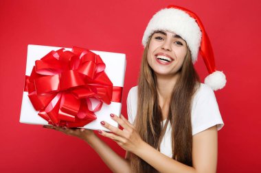 Güzel bir kadın Noel Baba şapkası takıyor ve elinde kırmızı bada hediye kutusu var.