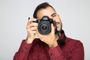 Gri arka planda kameralı genç fotoğrafçı