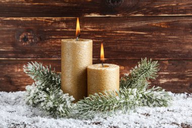 Kahverengi ahşap sırtında köknar ağacı dalları olan Noel mumları