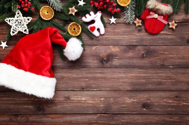 Noel ağacı dalları oyuncaklar ve kahverengi ahşap üzerinde Noel Baba şapkası 