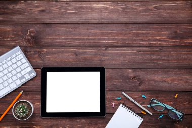 Kahverengi ağaçlık üzerinde ofis malzemeleri ile tablet ve bilgisayar klavyesi