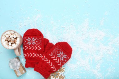 Hediye kutusuyla örülmüş eldivenler ve mavi sırtında bir fincan sıcak içecek.