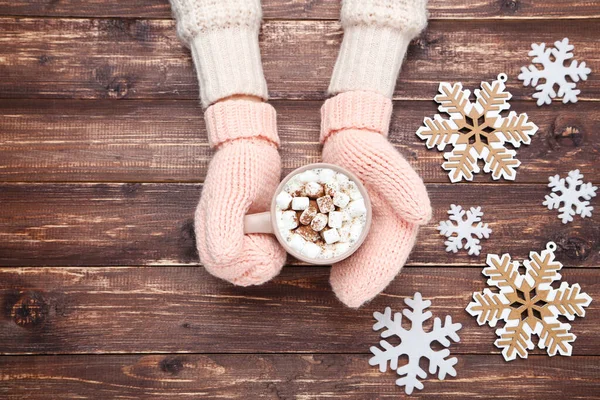 Hænder i strikkede vanter holder kop varm drink med snefnug - Stock-foto