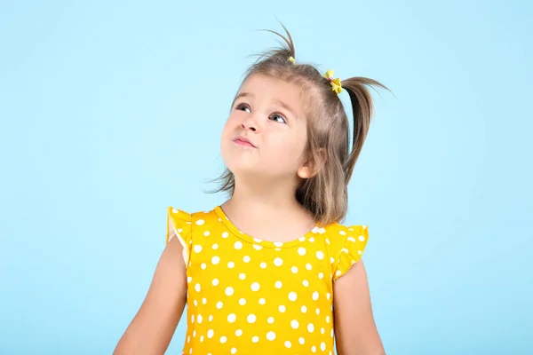 Мила маленька дівчинка в жовтій сукні на синьому фоні — стокове фото