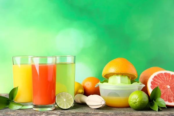 Citrus juice in glasses with fruits and juicer on wooden table — Stock Photo, Image