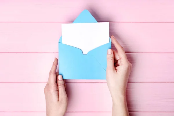 Kvinnliga händer med papper kuvert på rosa träbord — Stockfoto