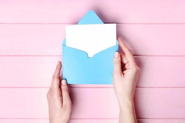 Mãos femininas com envelope de papel na mesa de madeira rosa — Fotografia de Stock