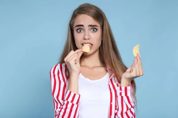 Młoda piękna dziewczyna z chipsami ziemniaczanymi na niebieskim tle — Zdjęcie stockowe