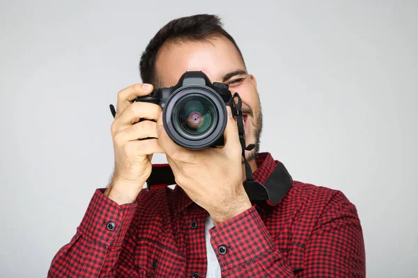 Gri arka planda kameralı genç fotoğrafçı