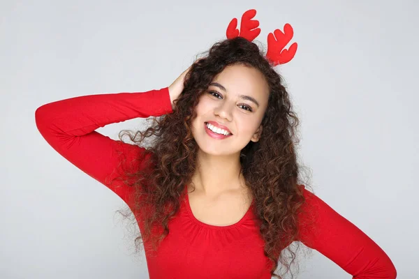 Beautiful american woman in red horns on grey background — Stock Photo, Image