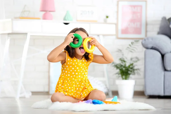 Mooi klein meisje spelen met regenboog speelgoed thuis — Stockfoto