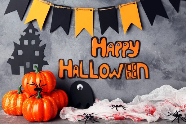 Tekst Happy Halloween met pompoenen en papieren vlaggen op grijze achterkant — Stockfoto