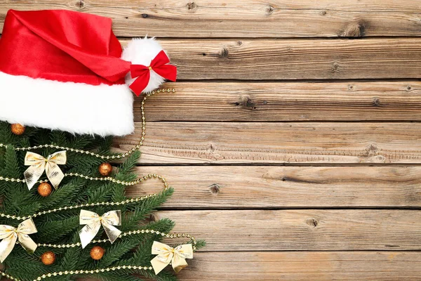 Ramas de árbol de Navidad con juguetes y sombrero de santa en madera marrón — Foto de Stock