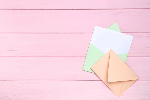 Envelopes de papel coloridos na mesa de madeira rosa — Fotografia de Stock