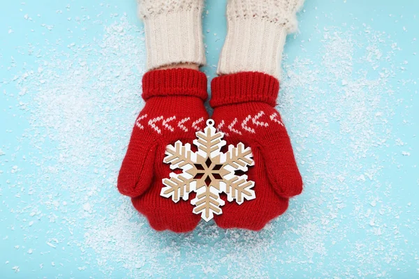 Händerna i stickade vantar håller trä snöflinga på blå bakgr — Stockfoto