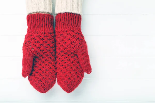 Hands in knitted mittens on white wooden table — Stock Photo, Image