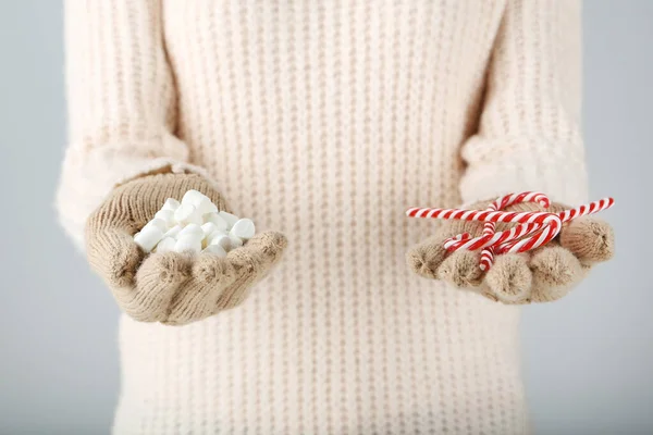 Händerna i stickade vantar håller godis och marshmallows på gre — Stockfoto