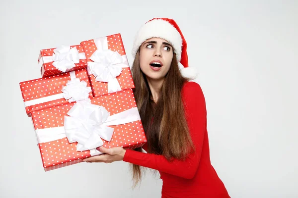 Mulher bonita usando chapéu de Papai Noel e segurando caixas de presente em cinza — Fotografia de Stock