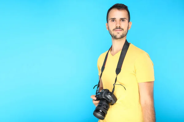 Young photographer with camera on blue background