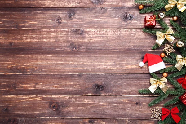 Ramuri de pom de Crăciun cu jucării și pălărie de santa pe lemn brun — Fotografie, imagine de stoc