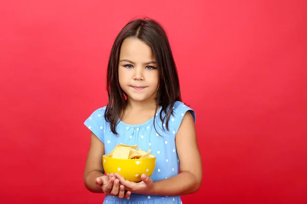 Menina bonita com batatas fritas na tigela em backgroun vermelho — Fotografia de Stock