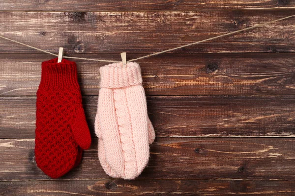 Strickhandschuhe hängen auf braunem Holzhintergrund — Stockfoto