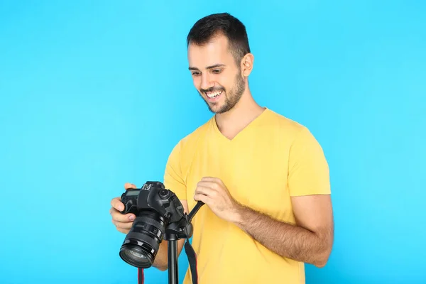 Junge Fotografin mit Kamera auf Stativ auf blauem Hintergrund — Stockfoto