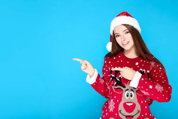 Hermosa mujer en jersey de Navidad y sombrero de santa en respaldo azul —  Fotos de Stock