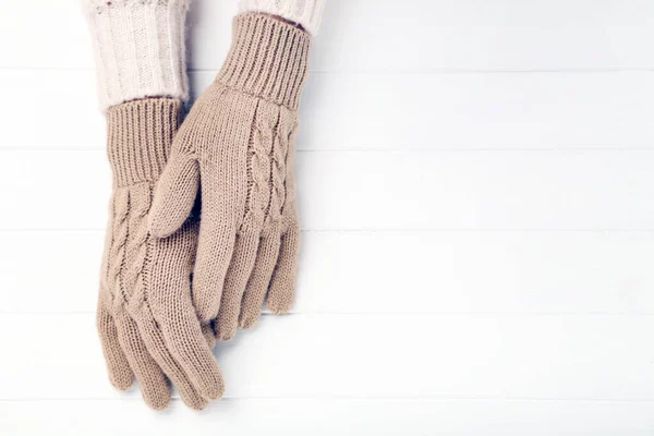 Hands in knitted mittens on white wooden table — Stock Photo, Image