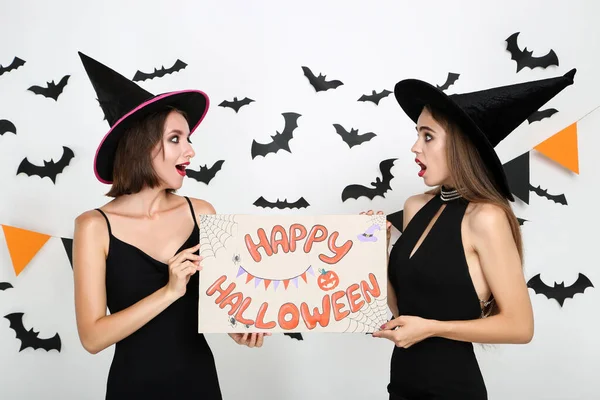 Dos mujeres jóvenes en trajes negros sosteniendo papel con texto Happy — Foto de Stock