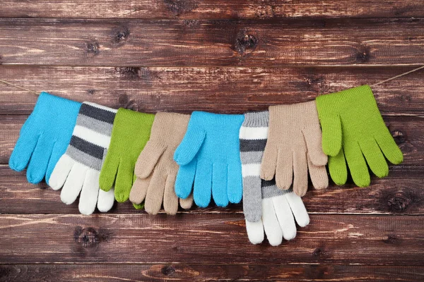 Πλεκτά γάντια που κρέμονται σε καφέ ξύλινο φόντο — Φωτογραφία Αρχείου