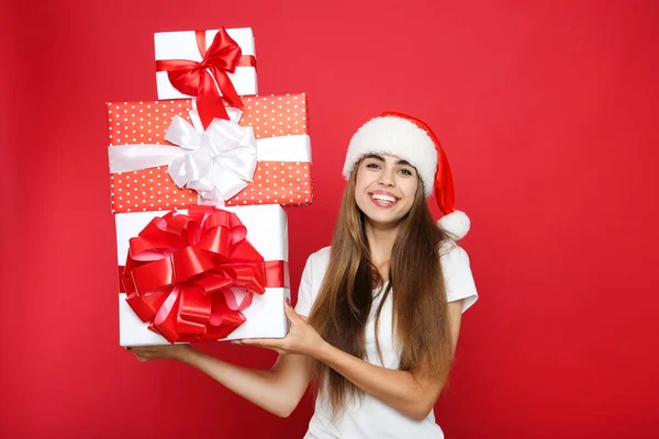 Mulher bonita vestindo chapéu de santa e segurando caixas de presente no vermelho — Fotografia de Stock