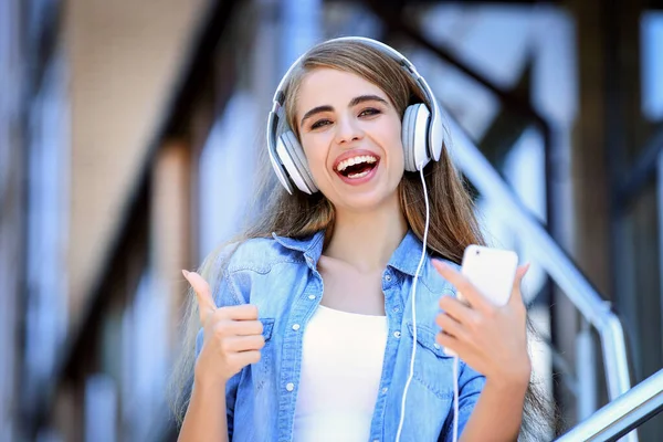 Joven hermosa chica escuchando música con auriculares y mostrando —  Fotos de Stock