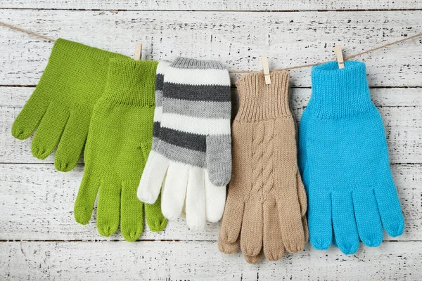 Πλεκτά γάντια που κρέμονται σε λευκό ξύλινο φόντο — Φωτογραφία Αρχείου