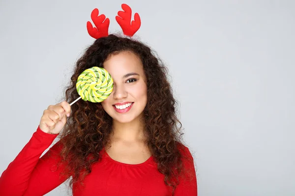 Mooi amerikaans vrouw in rood hoorns houden lolly op grijs b — Stockfoto