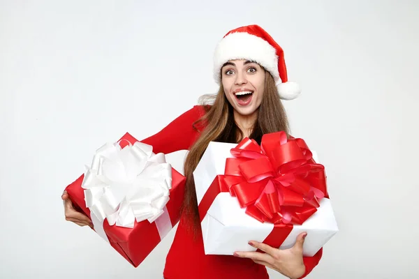 Bella donna con cappello da Babbo Natale e scatole regalo in mano su grigio — Foto Stock