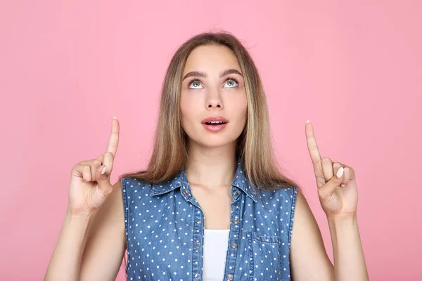 Vacker ung kvinna visar fingrarna upp på rosa bakgrund — Stockfoto