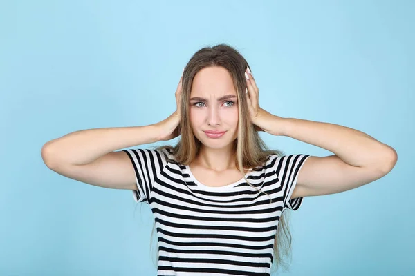 Hermosa mujer joven cerrando las orejas por las manos sobre fondo azul — Foto de Stock