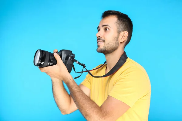 Joven fotógrafo con cámara sobre fondo azul —  Fotos de Stock