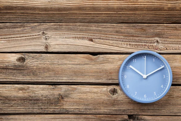 Blue round clock on brown wooden table — Stock Photo, Image